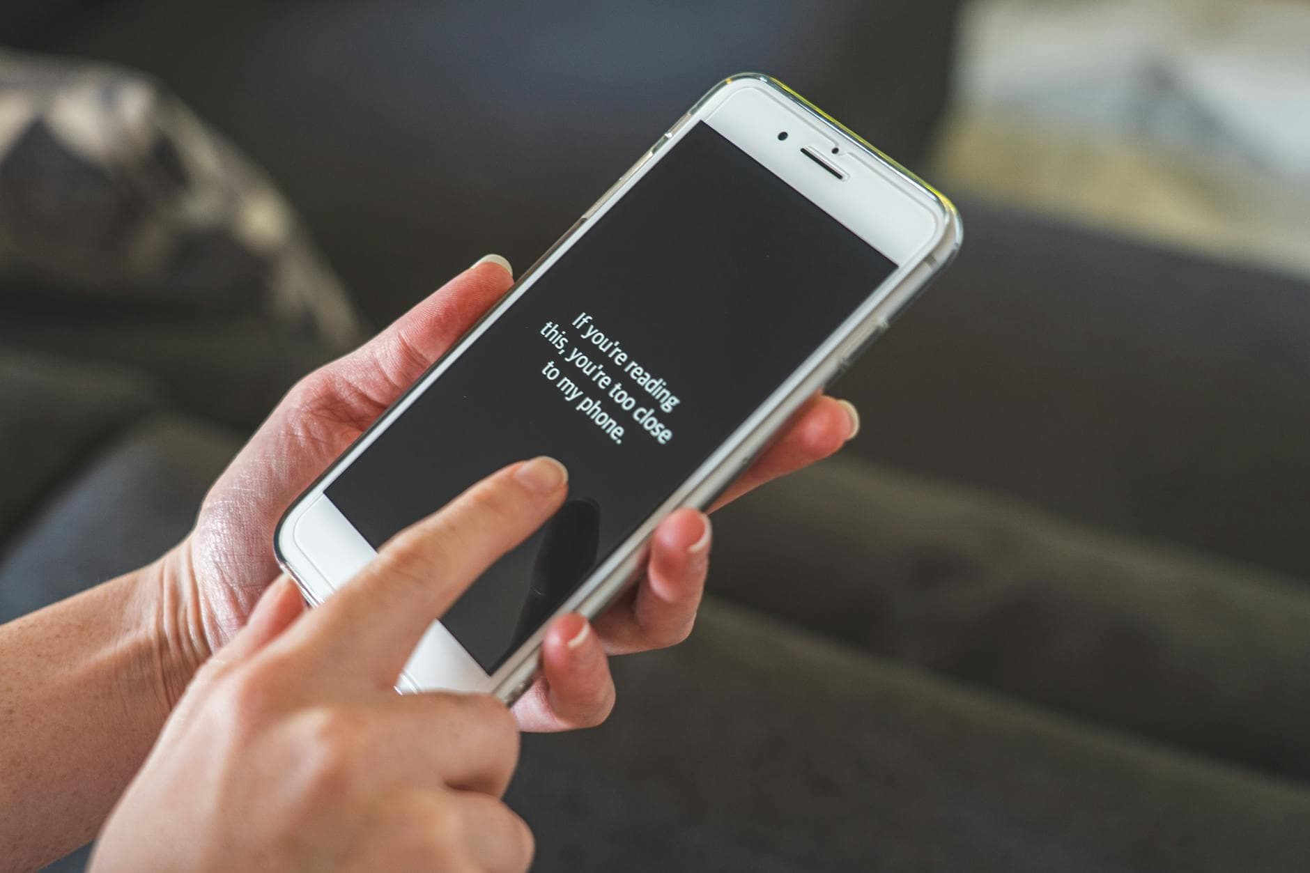 Person interacting with a smartphone indoors, emphasizing touch technology and communication.