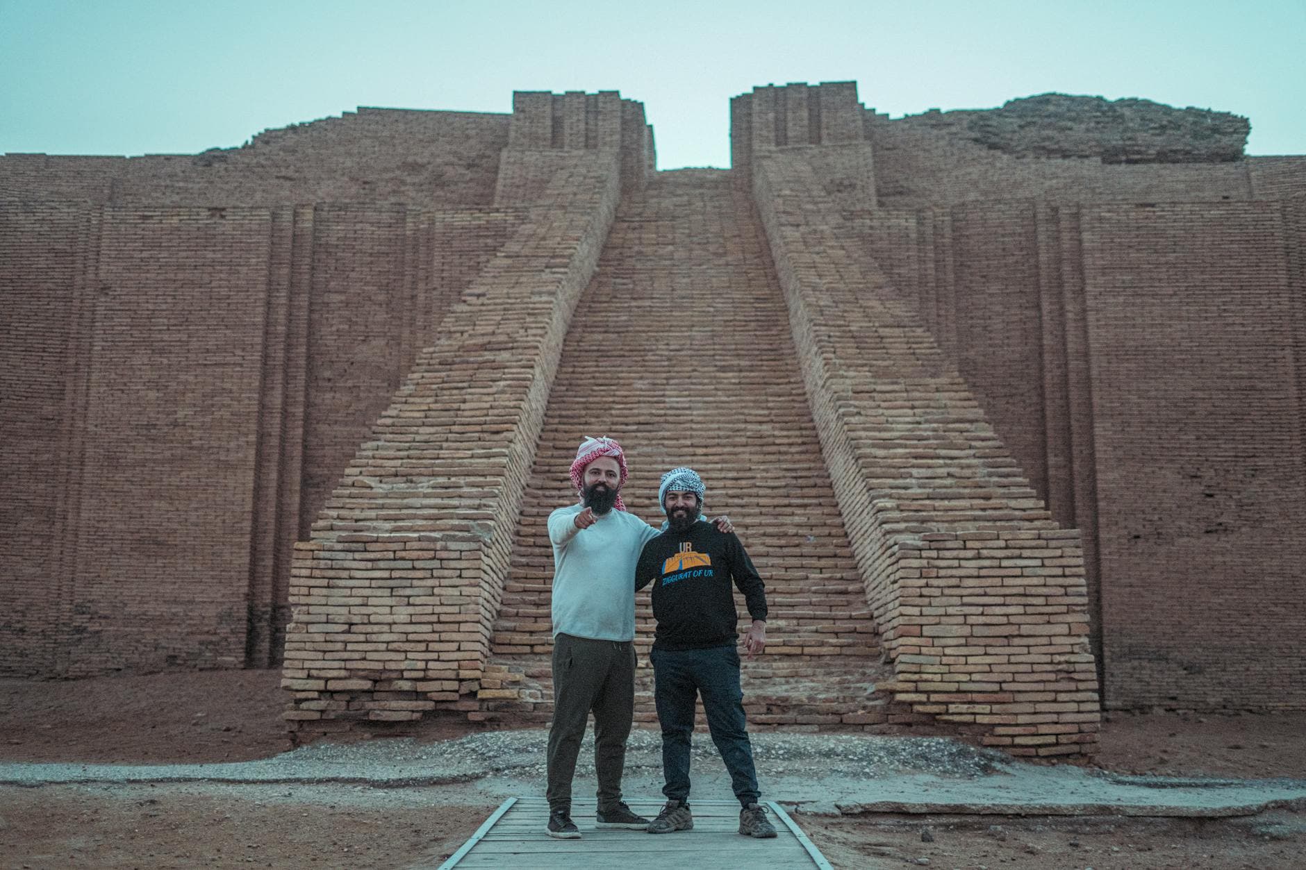 Two tourists pose at the ancient Ziggurat of Ur, a historical landmark in Iraq.
