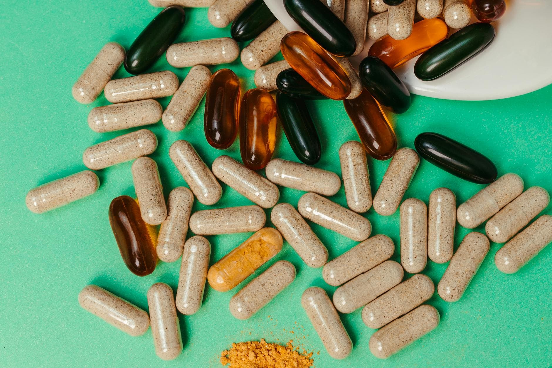 Various pills and capsules scattered on a green surface, symbolizing health supplements.