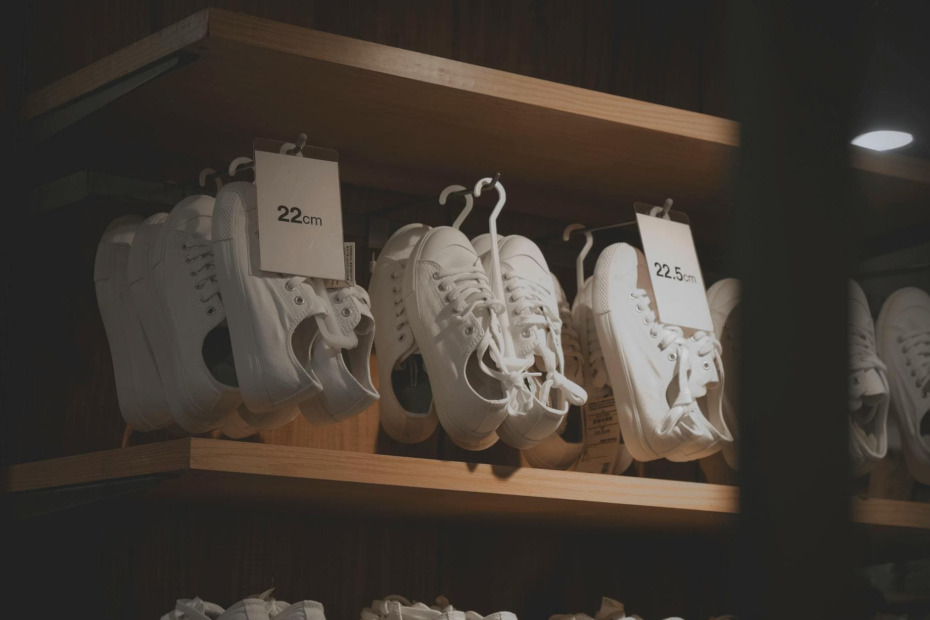 White sneakers elegantly displayed in a modern shop interior, showcasing minimalistic design on wooden shelves.