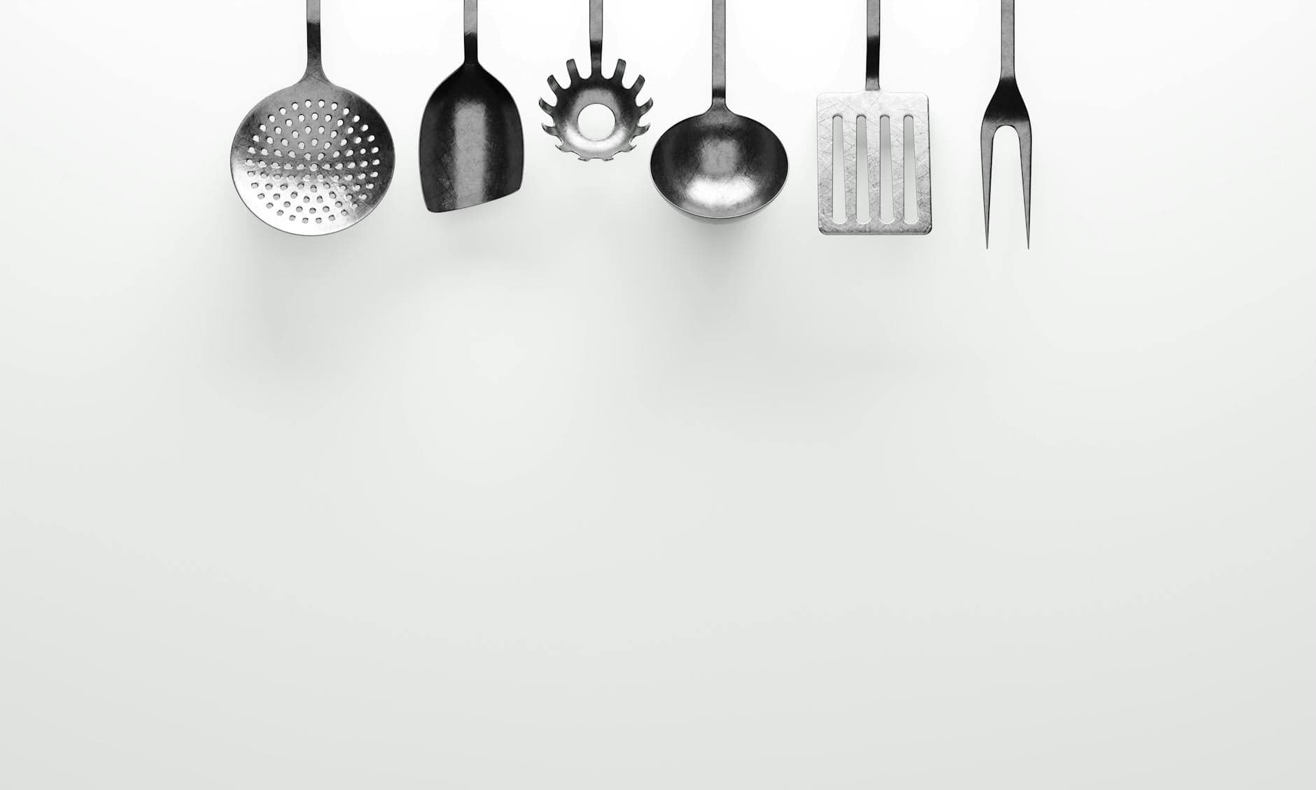 Hanging kitchen utensils against a clean white background, perfect for cooking themes.
