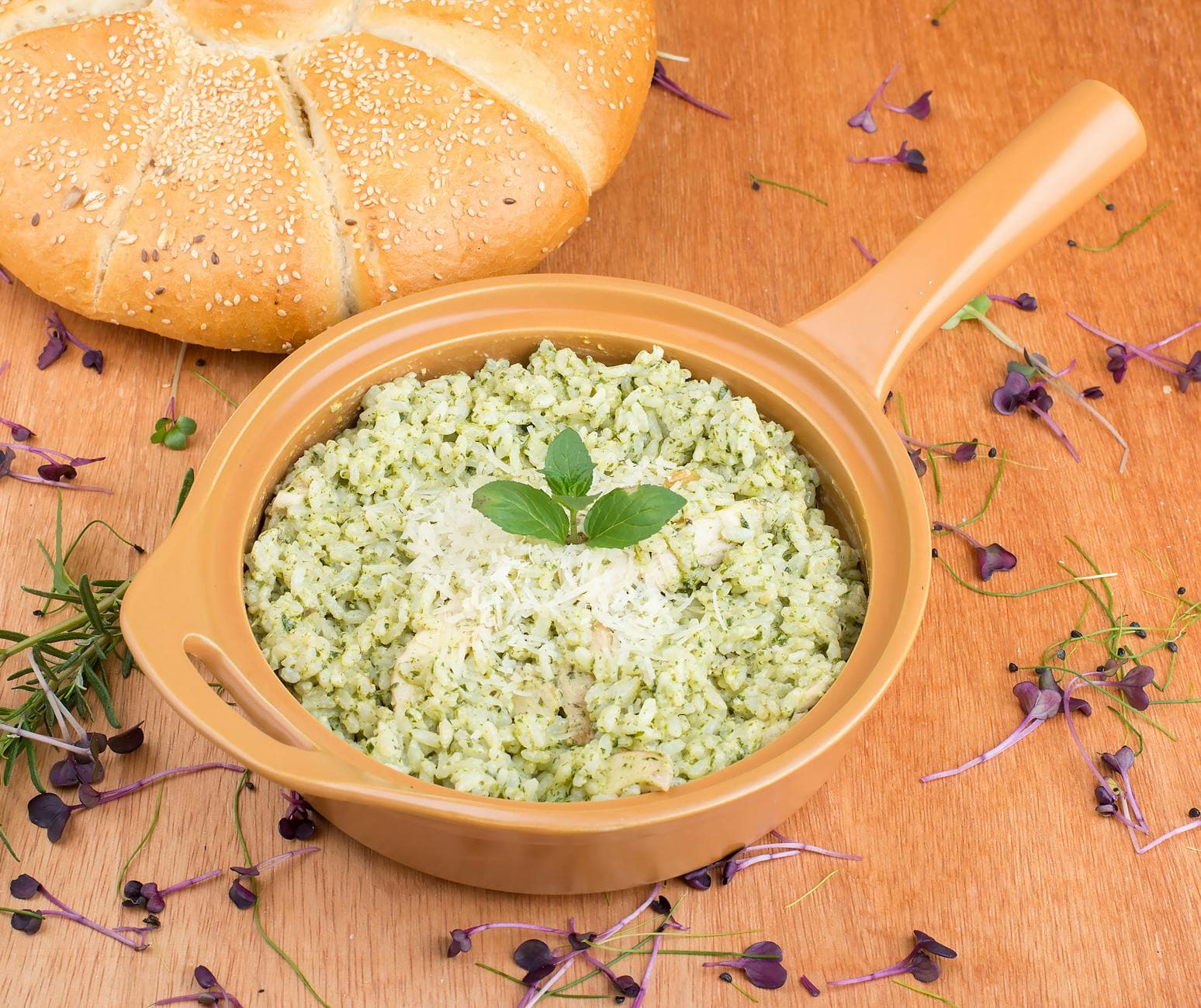 Delicious herb-infused risotto served with crusty bread, garnished with cheese and fresh herbs.