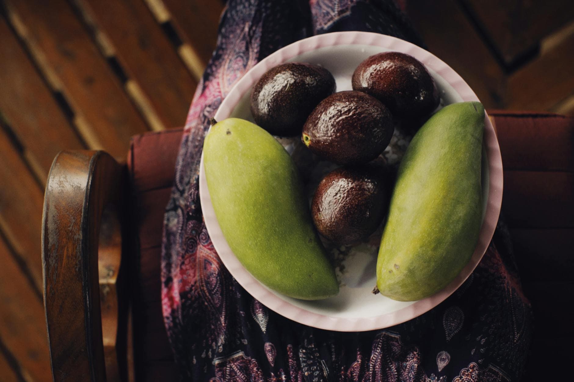 Close-up of ripe avocados and mangoes on a plate, showcasing fresh and healthy fruit.